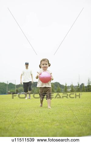 Girl with a ball and father following her View Large Photo Image Stock Photo - Girl with a ball and father following her. Fotosearch
