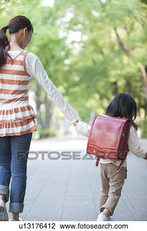 Girl with backpack holding mother's hand View Large Photo Image Stock Image - Girl with backpack holding mother's hand. Fotosearch