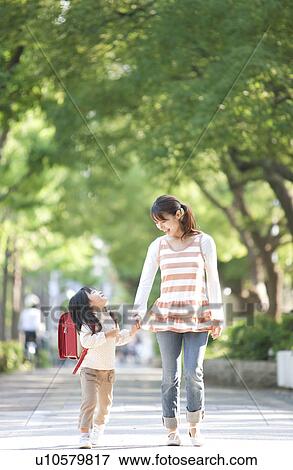 Stock Photo - Girl with backpack holding mother's hand, looking up. Fotosearch