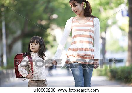 Stock Photo - Girl with backpack holding mother's hand, differential focus. Fotosearch