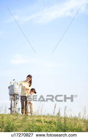 Girl with mother walking at riverbank, mother pushing bicycle View Large Photo Image Stock Photo - Girl with mother walking at riverbank, mother pushing bicycle. Fotosearch