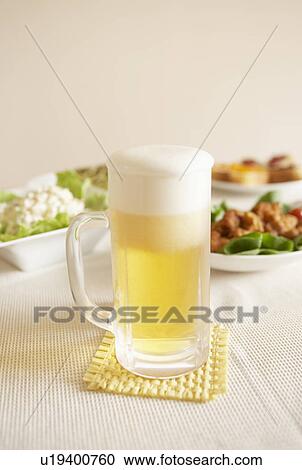 Stock Image - Glass of beer on table, white background. Fotosearch