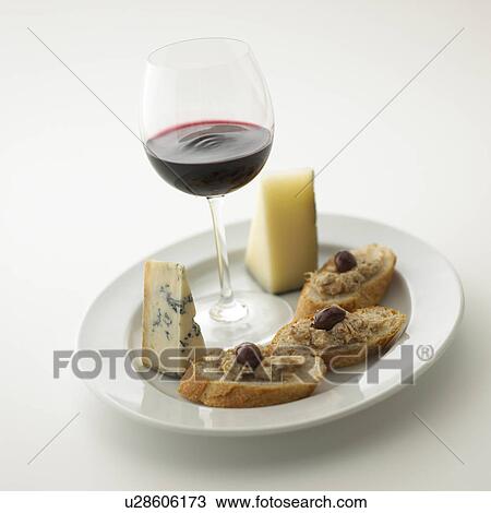 Stock Image - Glass of red wine and plate of cheese and bread, white background. Fotosearch