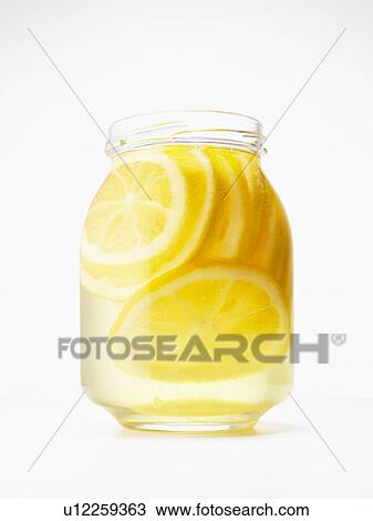 Stock Image - Jar of honey lemon preserve, white background. Fotosearch