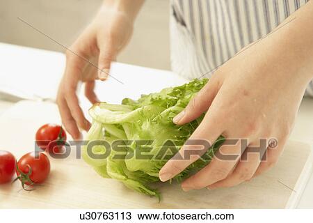 Stock Image - Lettuce and cherry tomatoes on cutting board, close up. Fotosearch