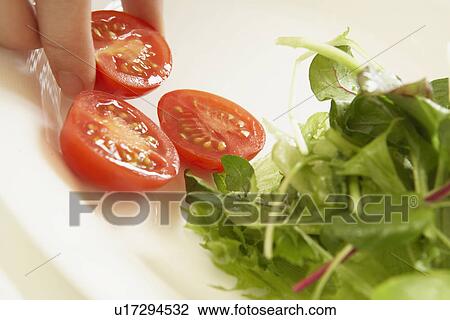 Stock Image - Lettuce and cherry tomatoes on plate, close up. Fotosearch