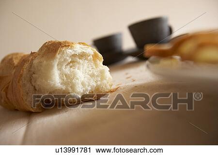 Stock Image - Loaf of bread and coffee cups, close up. Fotosearch