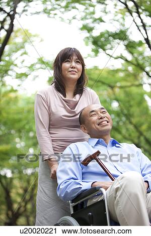 Mature couple in park, woman pushing man in wheelchair View Large Photo Image Stock Image - Mature couple in park, woman pushing man in wheelchair. Fotosearch