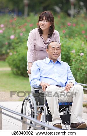 Mature couple in park, woman pushing man in wheelchair View Large Photo Image Stock Image - Mature couple in park, woman pushing man in wheelchair. Fotosearch
