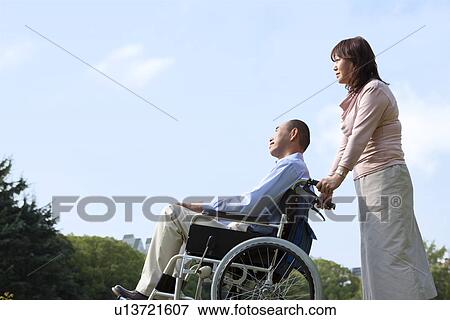 Mature couple in park, woman pushing man in wheelchair View Large Photo Image Stock Photo - Mature couple in park, woman pushing man in wheelchair. Fotosearch