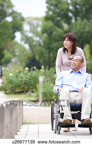 Mature couple in park, woman pushing man in wheelchair View Large Photo Image Stock Photo - Mature couple in park, woman pushing man in wheelchair. Fotosearch