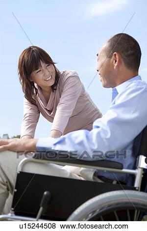 Stock Photo - Mature couple under sky, man in wheelchair. Fotosearch