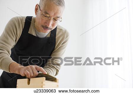 Stock Image - Mature man grating dried bonito. Fotosearch