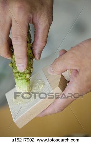 Stock Image - Mature man grating horseradish, close up. Fotosearch
