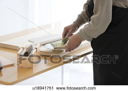 Stock Image - Mature man grating horseradish. Fotosearch