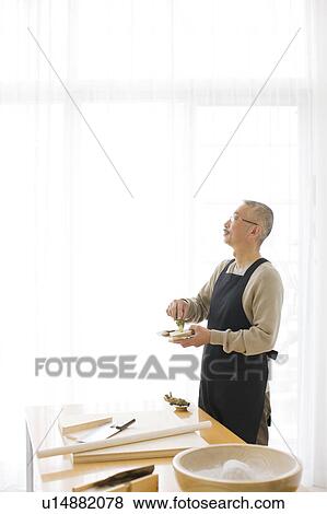 Stock Photo - Mature man grating horseradish. Fotosearch
