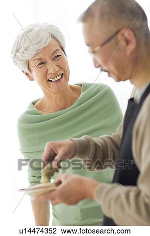 Stock Image - Mature man grating horseradish, white background. Fotosearch