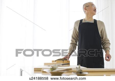 Stock Photo - Mature man in kitchen, looking away. Fotosearch