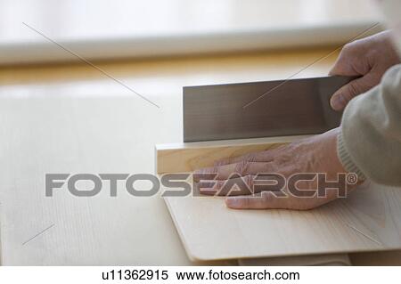 Stock Photography - Mature man making soba noodles, cutting dough, close up. Fotosearch
