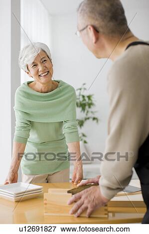 Stock Photo - Mature woman smiling to man grating dried bonito. Fotosearch