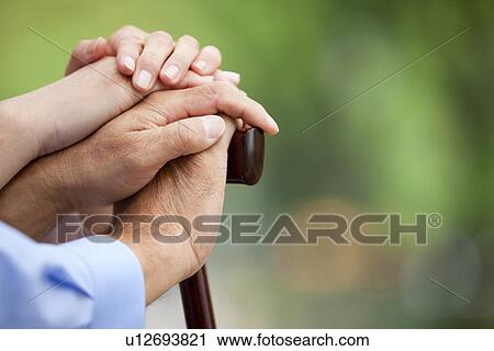 Stock Image - Mature woman stacking hands on top of man, close up, differential focus. Fotosearch