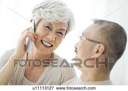 Stock Photo - Mature woman using mobile phone, smiling, close up. Fotosearch