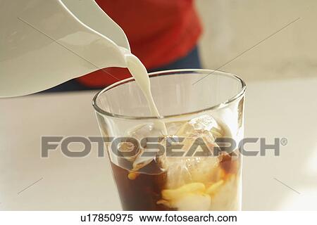 Milk pouring into glass of iced coffee, close up View Large Photo Image Stock Photography - Milk pouring into glass of iced coffee, close up. Fotosearch