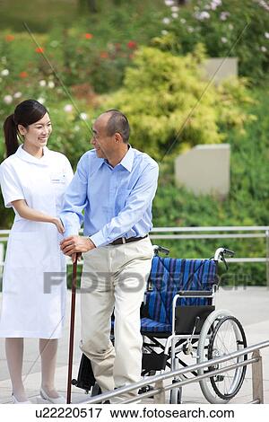 Nurse assisting man with cane out of wheelchair View Large Photo Image Stock Photo - Nurse assisting man with cane out of wheelchair. Fotosearch