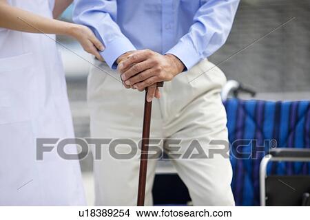 Picture - Nurse assisting man with cane. Fotosearch