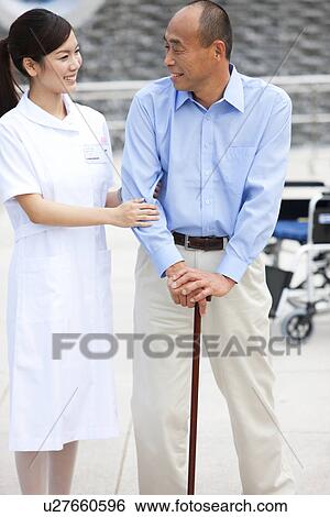 Stock Photograph - Nurse assisting man with cane. Fotosearch