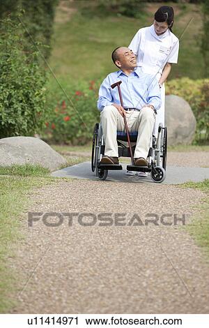 Stock Image - Nurse pushing man on wheelchair. Fotosearch