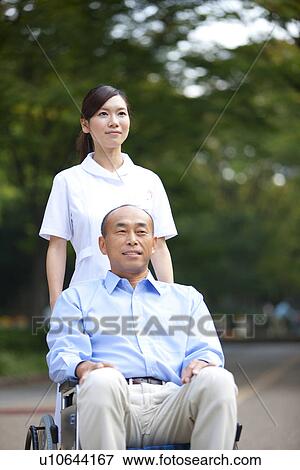 Stock Photo - Nurse pushing man on wheelchair. Fotosearch