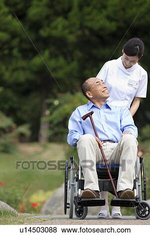 Nurse pushing man on wheelchair View Large Photo Image Stock Photo - Nurse pushing man on wheelchair. Fotosearch