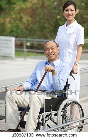 Stock Image - Nurse with a man on wheelchair. Fotosearch