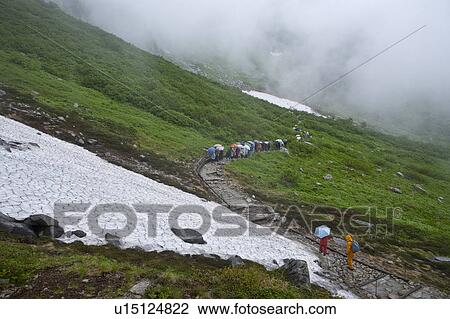 Stock Image - People walking down mountain road. Fotosearch