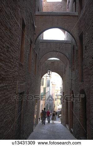Stock Photo - People Walking Down the Narrow Alley, Siena, Italy. Fotosearch