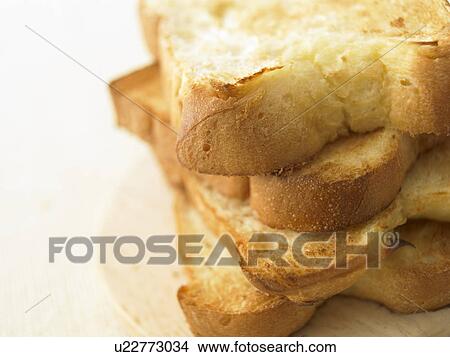 Picture - Pile of toast on cutting board, close up, white background. Fotosearch