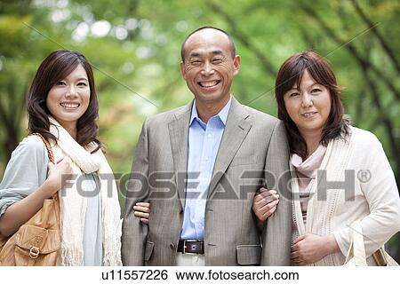 Stock Photograph - Portrait of family in park, smiling. Fotosearch