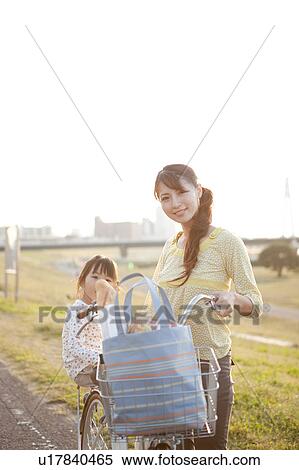Stock Photography - Portrait of girl and woman at riverbank, woman pushing bicycle. Fotosearch