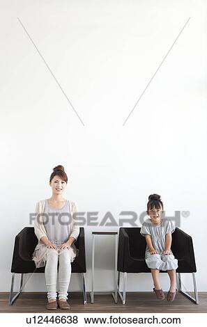 Stock Photo - Portrait of girl and woman sitting on sofa, white background. Fotosearch