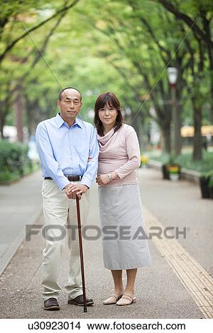 Portrait of mature couple at street, man holding walking stick View Large Photo Image Picture - Portrait of mature couple at street, man holding walking stick. Fotosearch