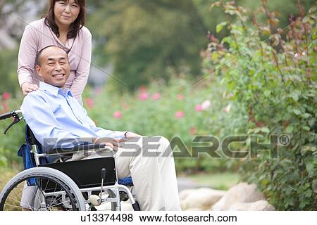 Portrait of mature couple in park, man in wheelchair View Large Photo Image Stock Photo - Portrait of mature couple in park, man in wheelchair. Fotosearch