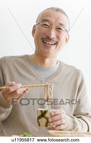 Portrait of mature man eating soba noodles, smiling, white background View Large Photo Image Stock Photo - Portrait of mature man eating soba noodles, smiling, white background. Fotosearch