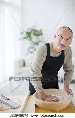 Picture - Portrait of mature man making soba noodles, making dough. Fotosearch