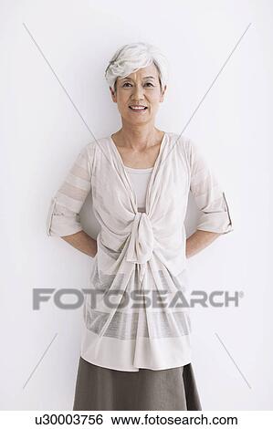 Stock Photograph - Portrait of mature woman, smiling, white background. Fotosearch