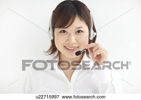 Stock Photo - Portrait of young businesswoman wearing headset, smiling, white background. Fotosearch