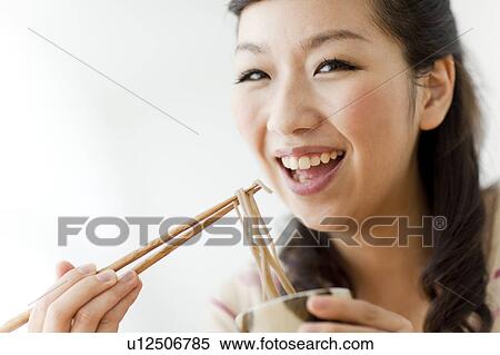 Portrait of young woman eating soba noodles, smiling, white background View Large Photo Image Stock Photography - Portrait of young woman eating soba noodles, smiling, white background. Fotosearch