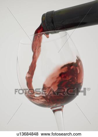 Stock Photo - Red wine pouring into grass, close up, white background. Fotosearch