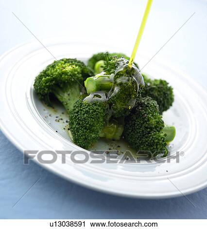Stock Image - Salad dressing being poured on broccoli. Fotosearch