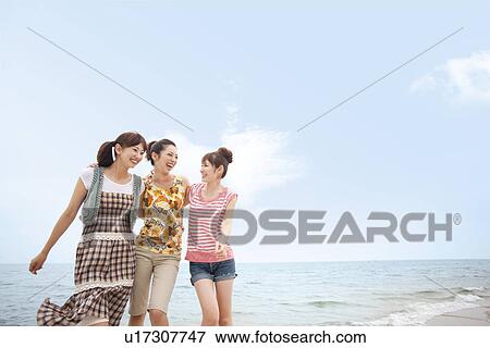 Three young women walking side by side at beach View Large Photo Image Stock Photo - Three young women walking side by side at beach. Fotosearch